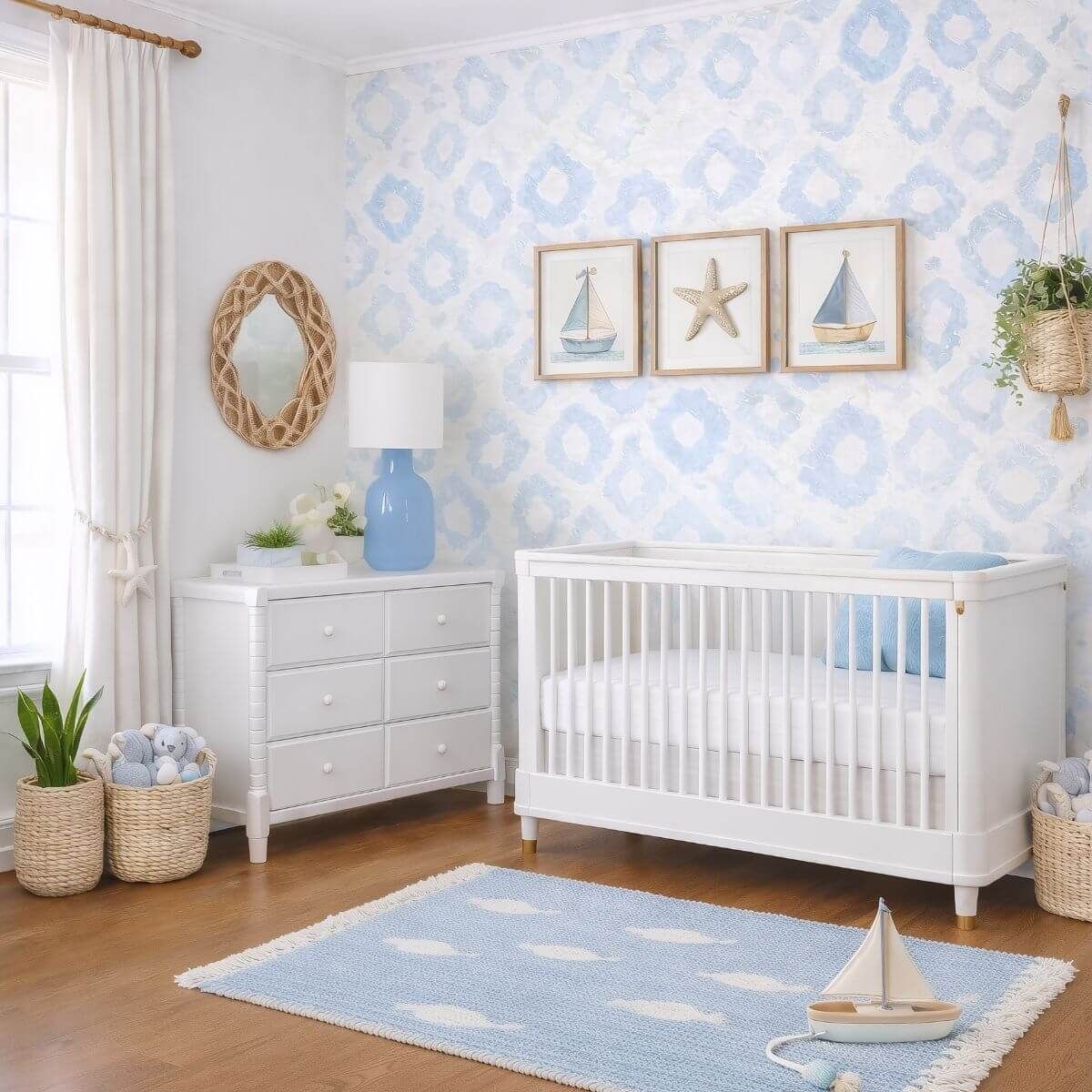 Light blue coastal nursery with patterned wallpaper, a white crib, sailboat wall art, and a pale blue rug.